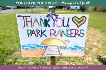A hand-drawn sign reading "Thank you park rangers" with a beach and heart. The sign is on a stake in the grass.