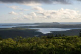 A landscape view of an estuary surrounded by lush green hillside.