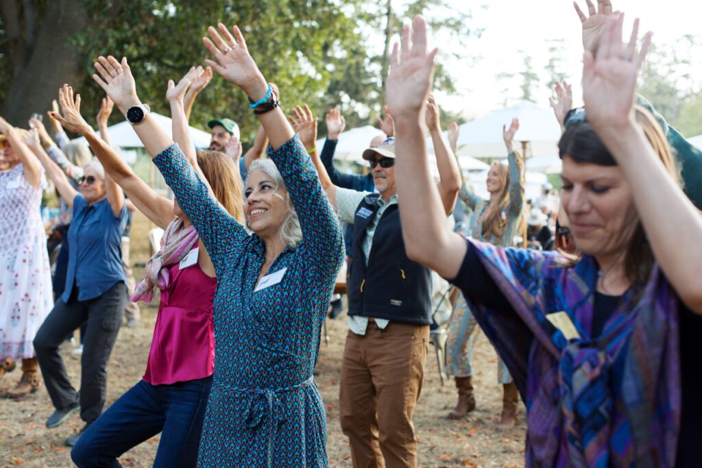 Many people put their hands in the air as they dance and smile.