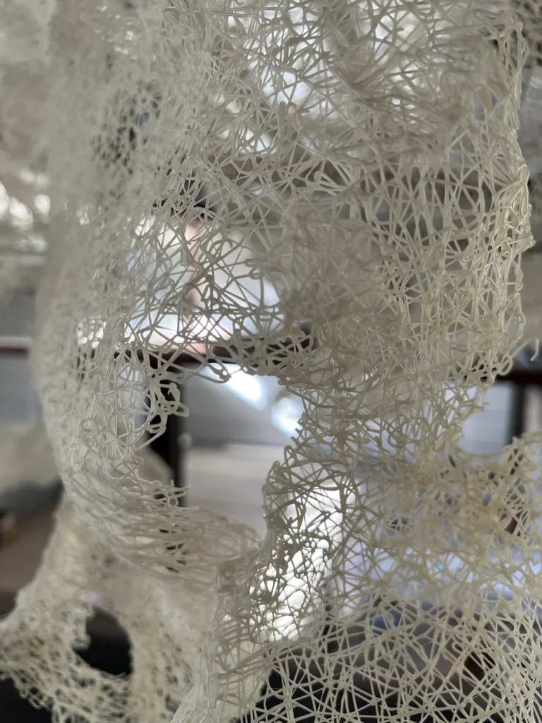A close-up of a sculptural piece created from white bioplastic filaments.
