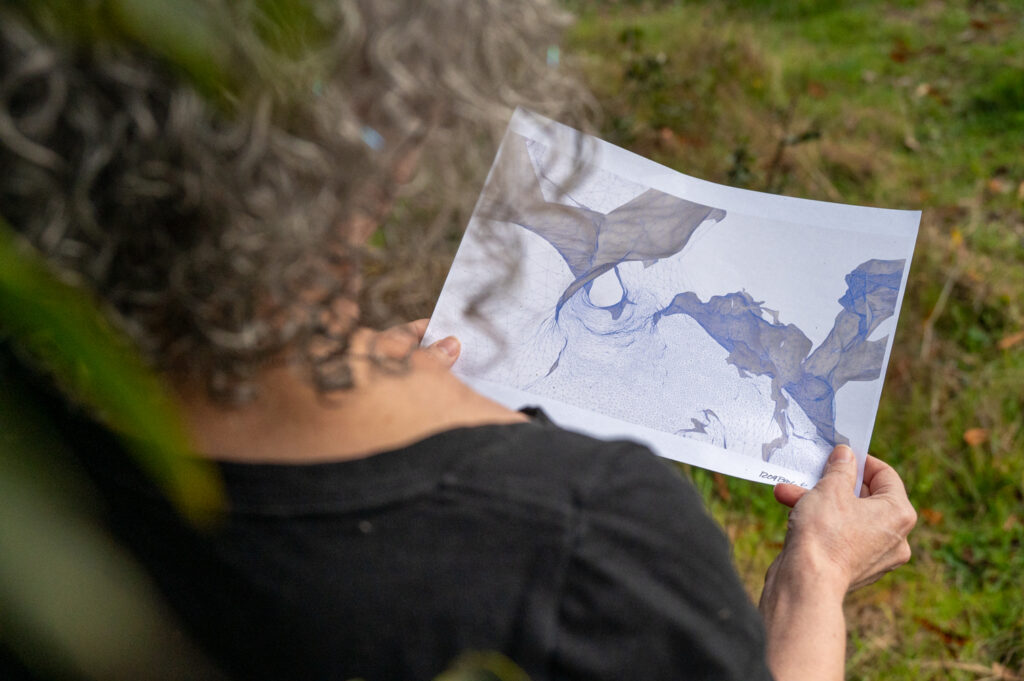 An over-the-shoulder view of a person holding a paper featuring a 3D model.